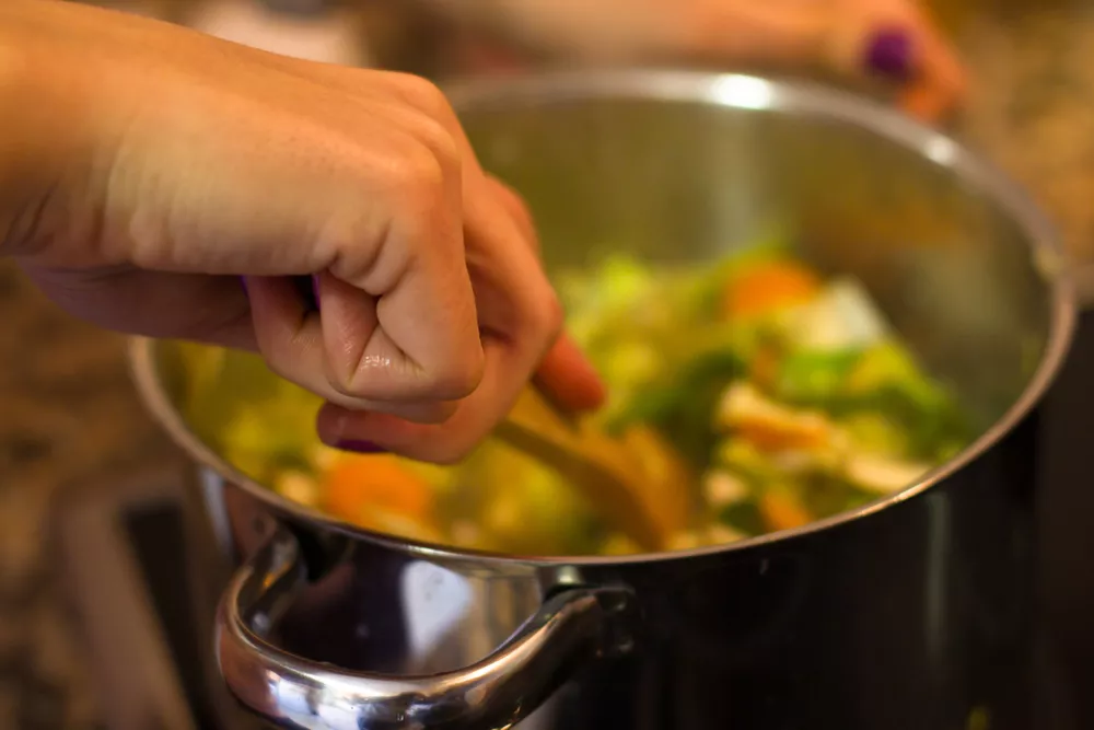 iemand roert door een pan met soep