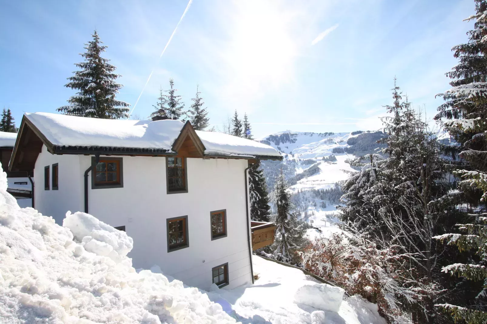 huisje onder sneeuw in de bossen, met bergen op de achtergrond