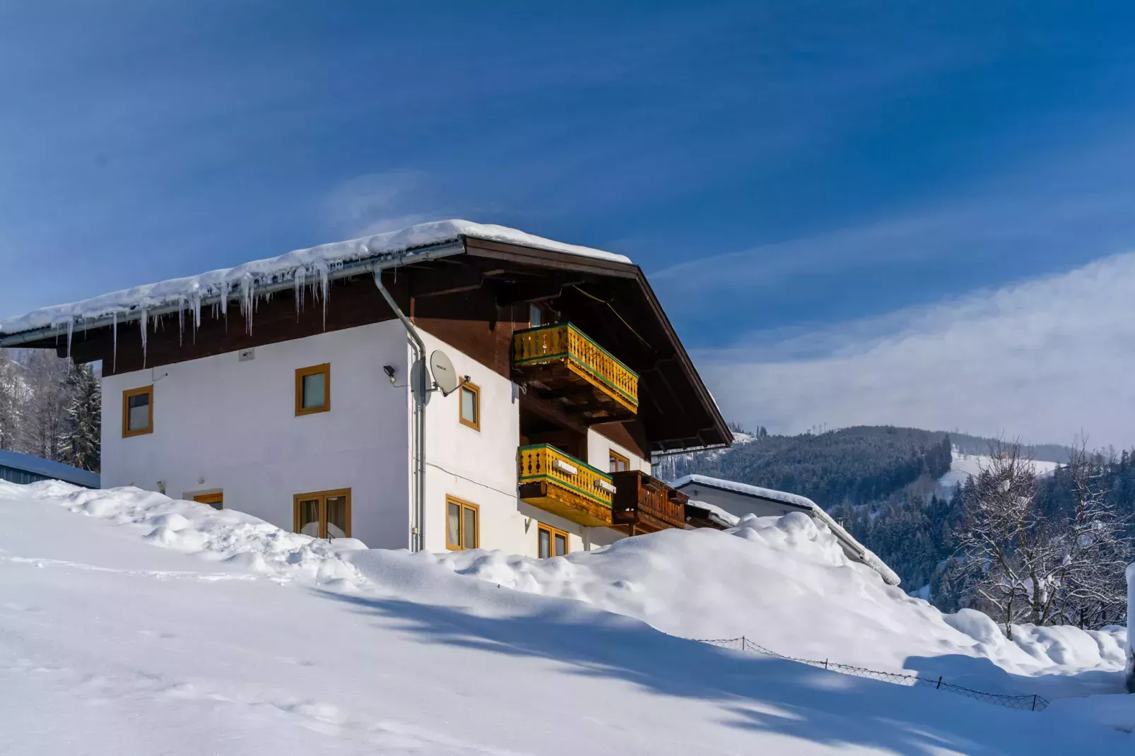 Huis onder sneeuw in de bergen, met bergen in de achtergrond