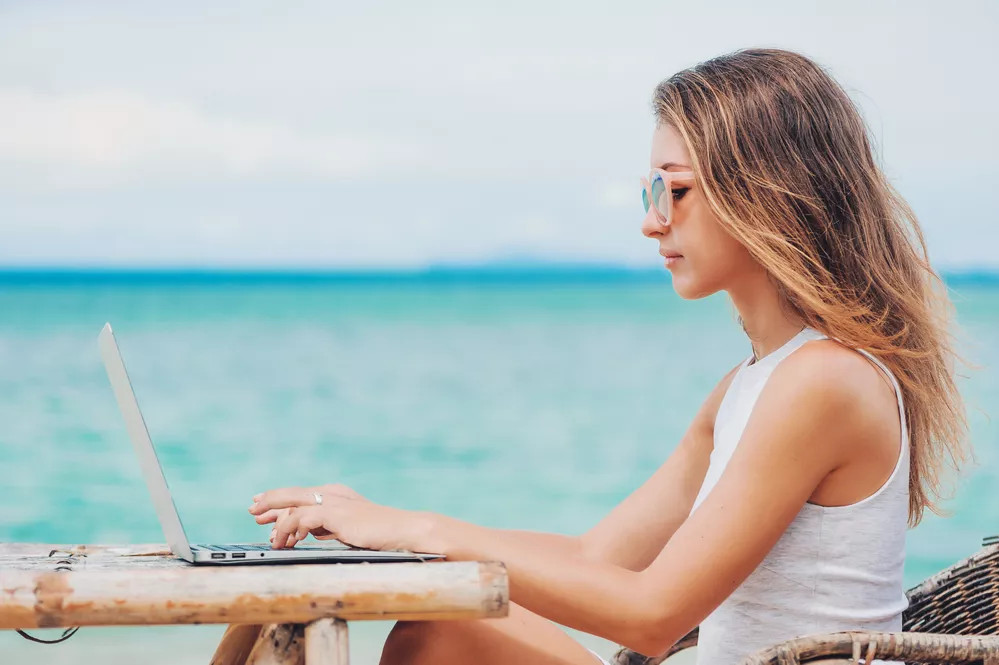 Vrouw aan het werk op een laptop bij het strand